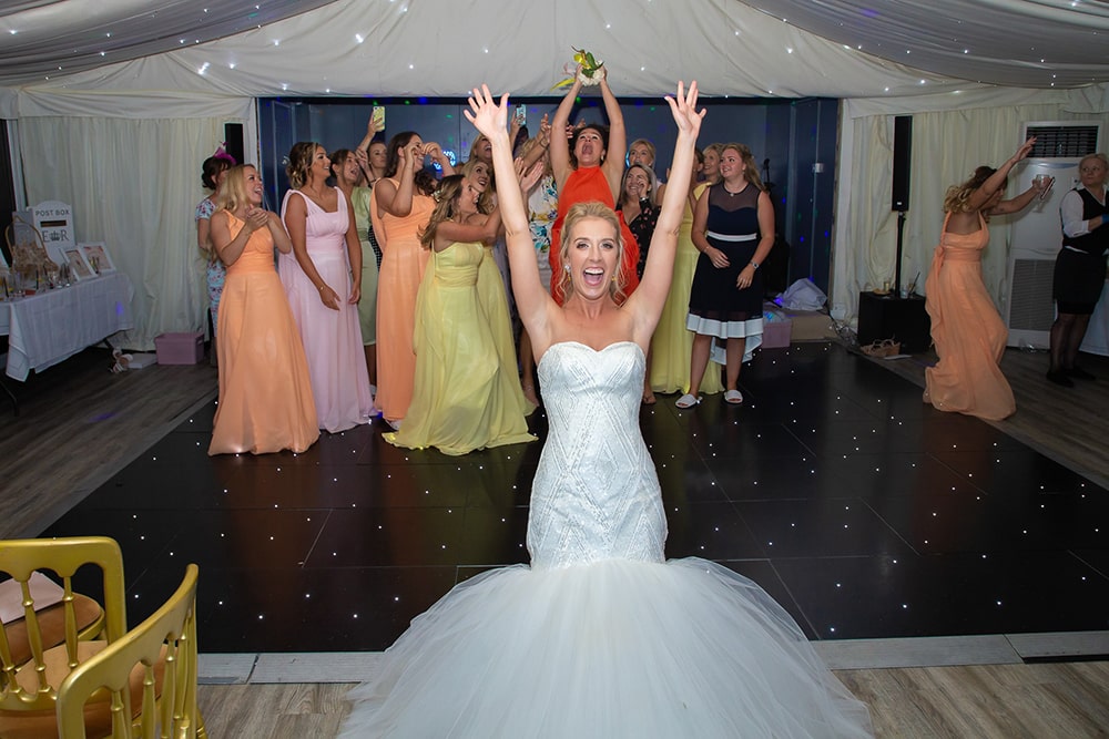 Happy bride with her hands up, and group of ladies standing behind