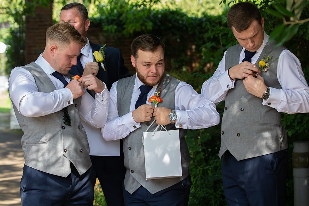 Groom and three men attaching small flowers to their suits